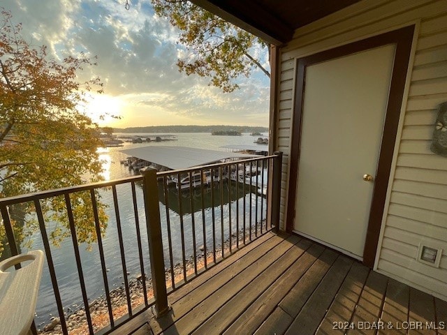 balcony at dusk featuring a water view