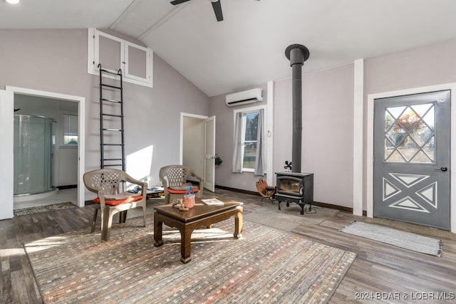 living room with wood-type flooring, an AC wall unit, a wood stove, ceiling fan, and lofted ceiling