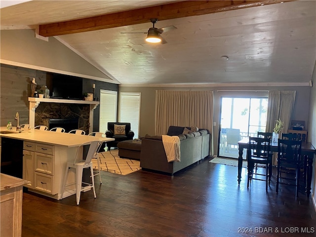 living room with lofted ceiling with beams, sink, a fireplace, and dark hardwood / wood-style flooring