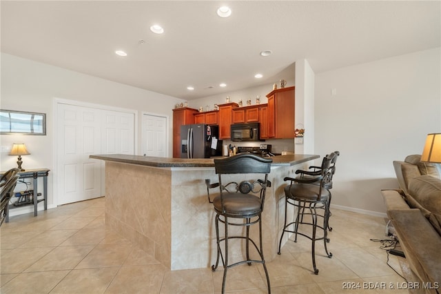 kitchen with a kitchen breakfast bar, light tile patterned flooring, stainless steel fridge with ice dispenser, and kitchen peninsula