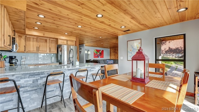 kitchen with light stone countertops, wood ceiling, appliances with stainless steel finishes, and light hardwood / wood-style flooring