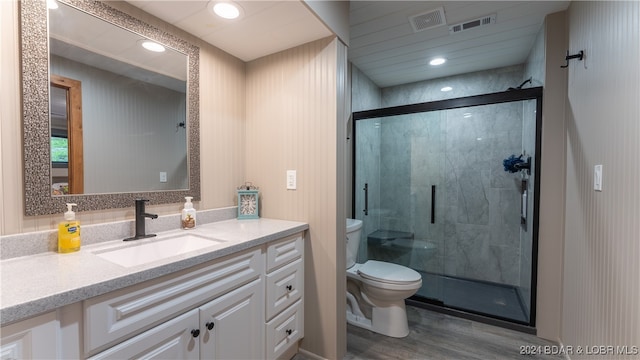 bathroom featuring a shower with door, vanity, wood-type flooring, and toilet