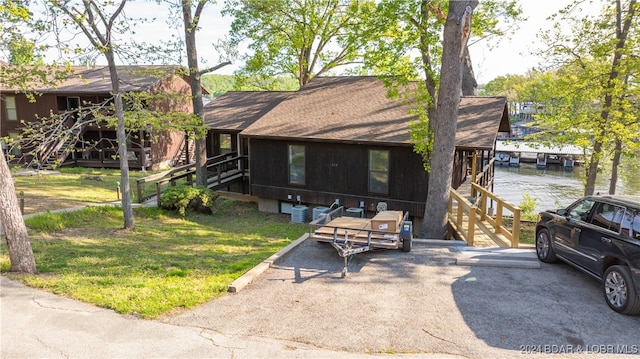 view of front of property with central air condition unit, a front yard, and a water view