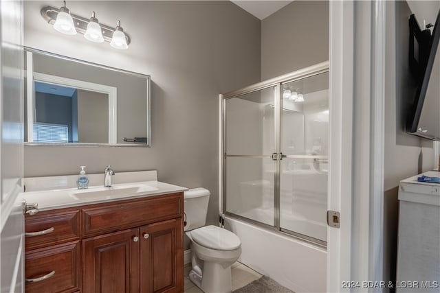 full bathroom featuring vanity, toilet, combined bath / shower with glass door, and tile patterned flooring