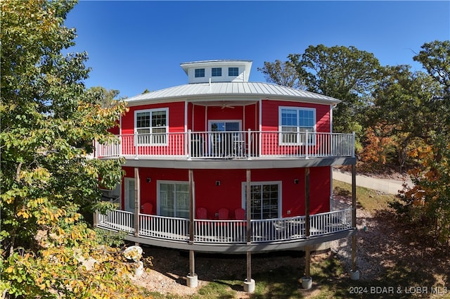 rear view of house with ceiling fan and a balcony