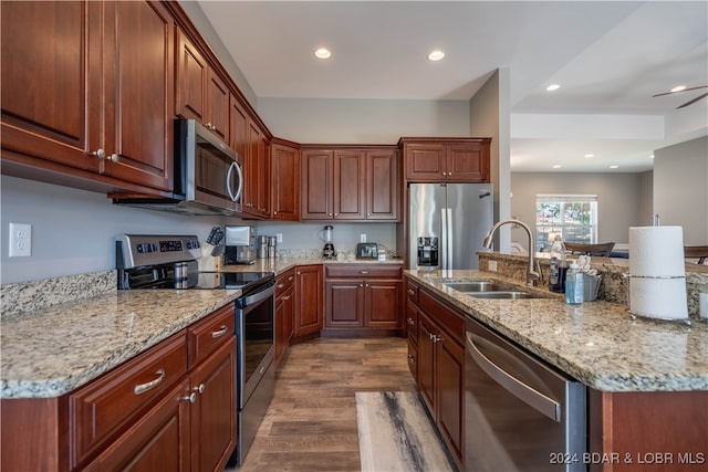 kitchen featuring light stone countertops, hardwood / wood-style flooring, stainless steel appliances, and sink