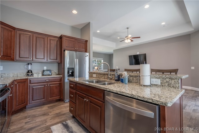 kitchen with an island with sink, stainless steel appliances, sink, and dark hardwood / wood-style flooring