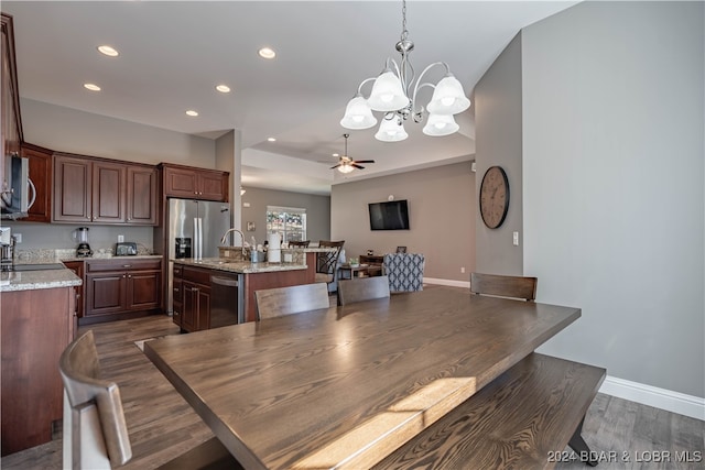 dining space with dark wood-type flooring, sink, and ceiling fan with notable chandelier