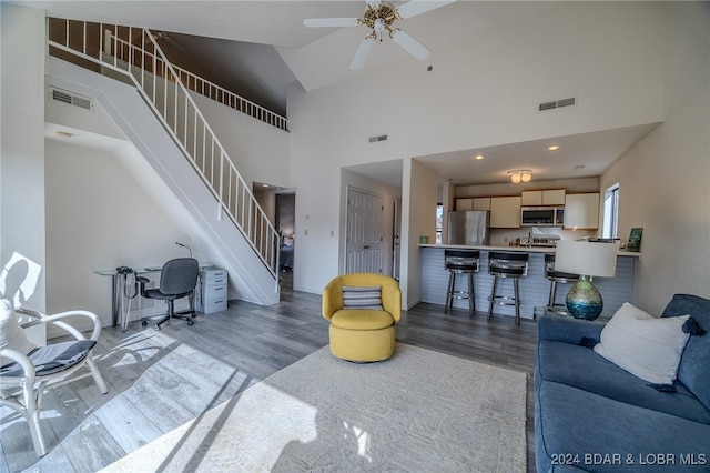 living room with light hardwood / wood-style floors, high vaulted ceiling, and ceiling fan