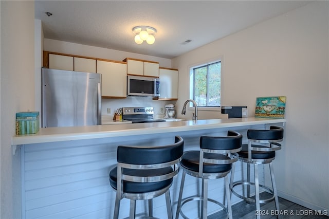 kitchen with appliances with stainless steel finishes, kitchen peninsula, a textured ceiling, and sink