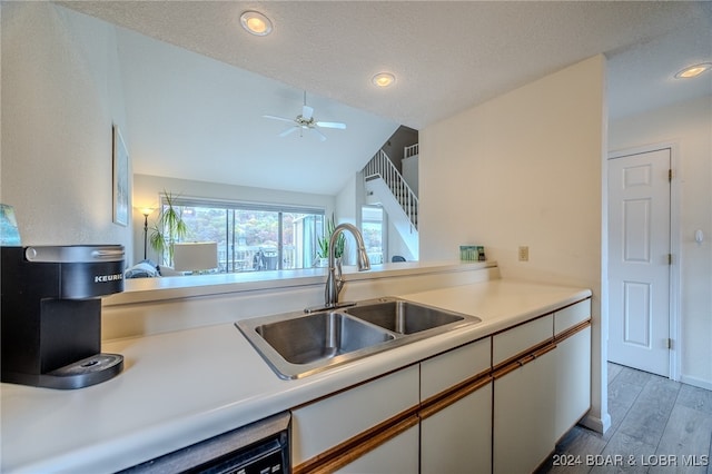 kitchen with light hardwood / wood-style flooring, sink, vaulted ceiling, white cabinetry, and ceiling fan