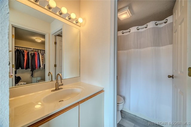 bathroom with vanity, curtained shower, a textured ceiling, and toilet