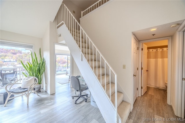 stairway with hardwood / wood-style flooring and a towering ceiling