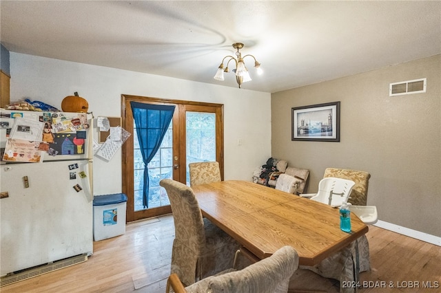 dining room with a notable chandelier, french doors, and light wood-type flooring