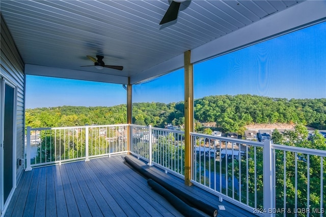 deck featuring a ceiling fan and a forest view