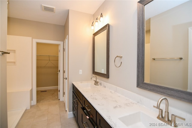 bathroom featuring a spacious closet, double vanity, a sink, and visible vents