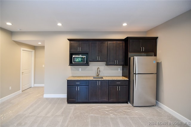 kitchen with freestanding refrigerator, a sink, baseboards, and dark brown cabinets