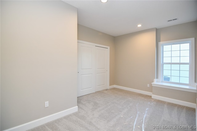 empty room with recessed lighting, visible vents, light carpet, and baseboards