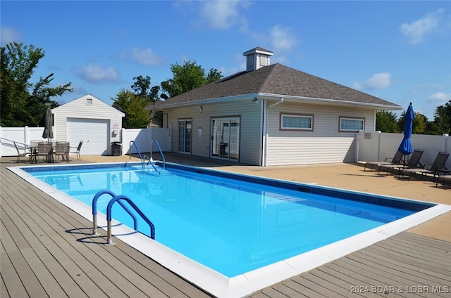 view of pool featuring a garage, an outbuilding, and a wooden deck