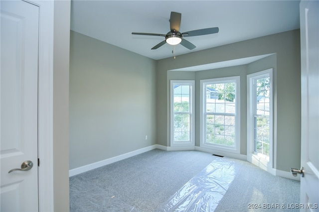 unfurnished room with light colored carpet and ceiling fan