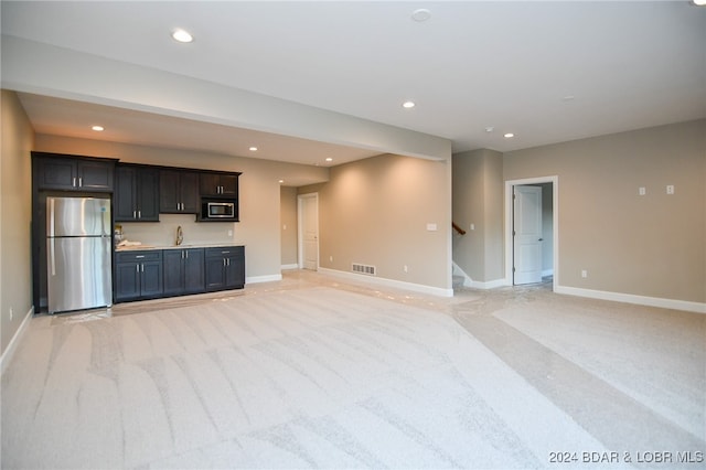 unfurnished living room with sink and light colored carpet