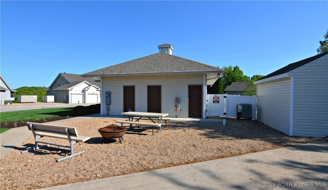 view of front of house featuring a garage, an outdoor fire pit, a patio, and central AC unit