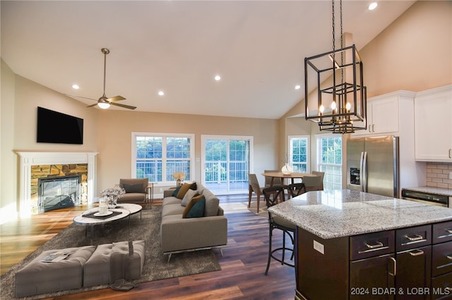 kitchen with decorative backsplash, dark hardwood / wood-style floors, stainless steel fridge, white cabinets, and a fireplace