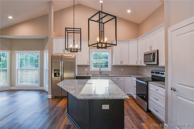 kitchen featuring light stone countertops, appliances with stainless steel finishes, a kitchen island, hanging light fixtures, and dark hardwood / wood-style floors