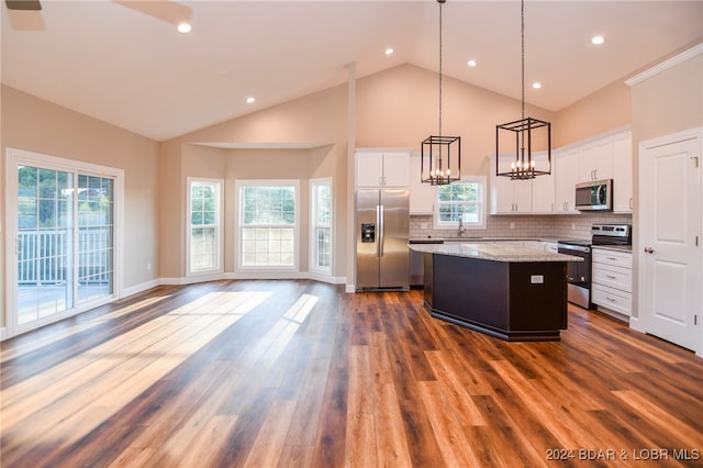 kitchen featuring a center island, stainless steel appliances, pendant lighting, white cabinets, and dark hardwood / wood-style floors