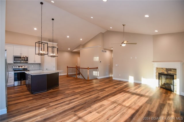 kitchen with hardwood / wood-style flooring, a center island, white cabinetry, appliances with stainless steel finishes, and high vaulted ceiling