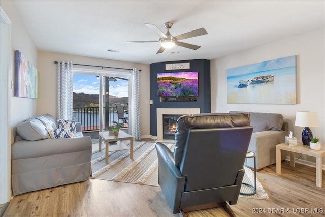 living room featuring a fireplace, wood-type flooring, and ceiling fan