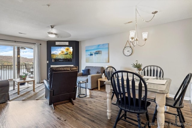 dining space with hardwood / wood-style flooring and ceiling fan with notable chandelier