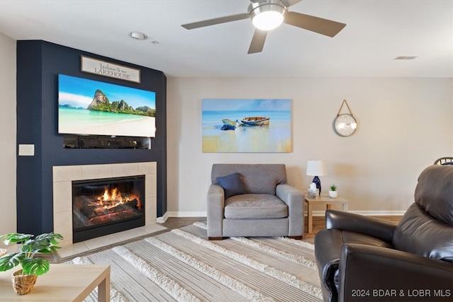 living room featuring a tiled fireplace, hardwood / wood-style flooring, and ceiling fan