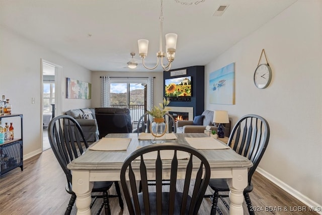 dining room with wood-type flooring and ceiling fan with notable chandelier