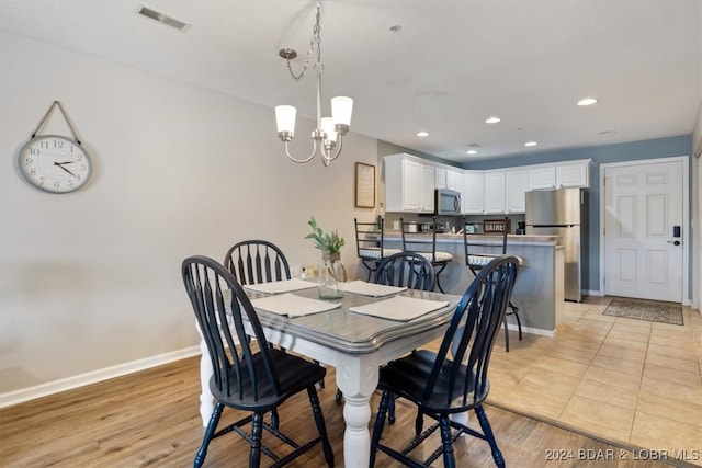 dining space featuring light hardwood / wood-style floors and an inviting chandelier