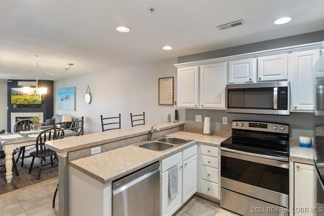 kitchen featuring a kitchen breakfast bar, kitchen peninsula, white cabinets, and stainless steel appliances