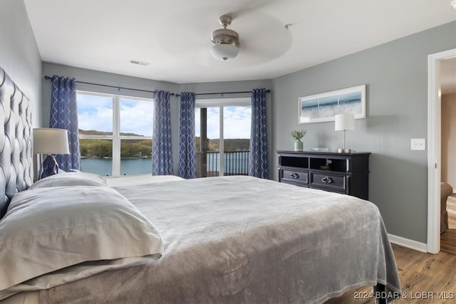 bedroom featuring hardwood / wood-style flooring, a water view, and ceiling fan