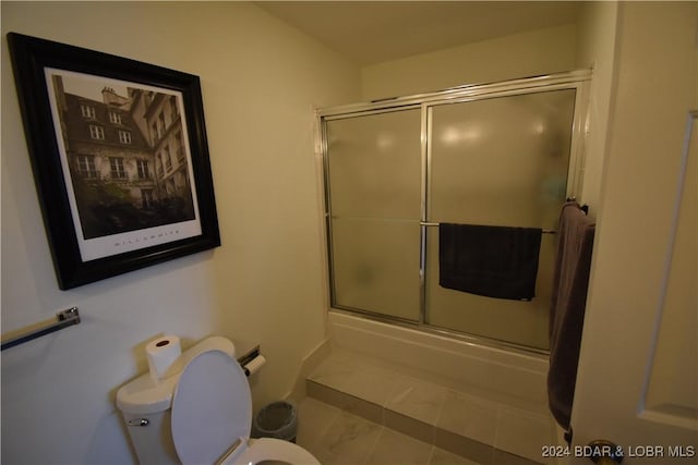 bathroom featuring shower / bath combination with glass door, toilet, and tile patterned flooring