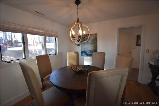 dining space with hardwood / wood-style floors and a notable chandelier