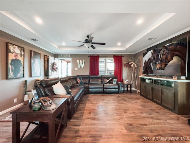 living room featuring a tray ceiling, ceiling fan, hardwood / wood-style floors, and ornamental molding