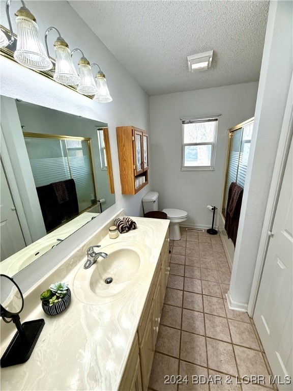 bathroom with walk in shower, tile patterned floors, a textured ceiling, toilet, and vanity