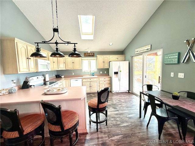 kitchen featuring a skylight, white appliances, sink, dark hardwood / wood-style floors, and hanging light fixtures