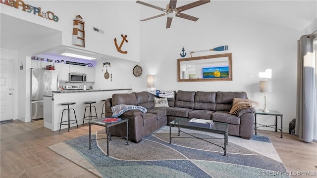 living room with a high ceiling, light hardwood / wood-style flooring, and ceiling fan