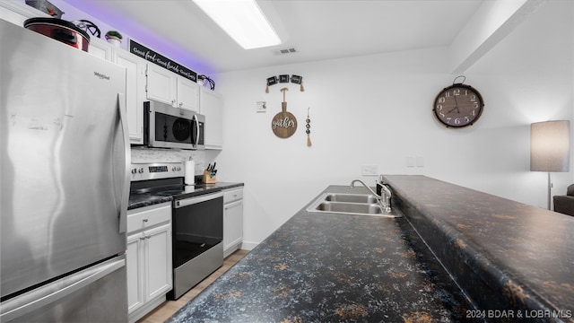 kitchen with sink, white cabinetry, stainless steel appliances, and decorative backsplash