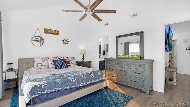 bedroom featuring ensuite bathroom, light hardwood / wood-style flooring, ceiling fan, and a towering ceiling