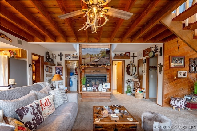 living room featuring beamed ceiling, wooden walls, wood ceiling, and ceiling fan