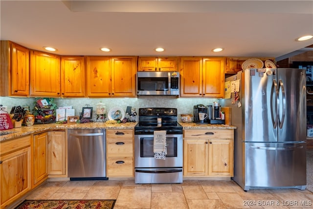 kitchen with appliances with stainless steel finishes, tasteful backsplash, and light stone counters