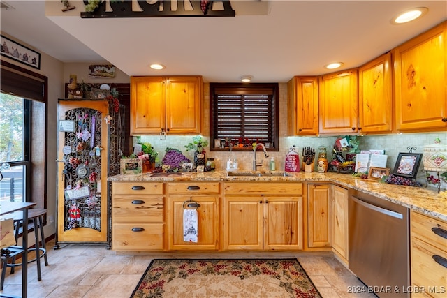 kitchen with dishwasher, light stone counters, sink, and backsplash