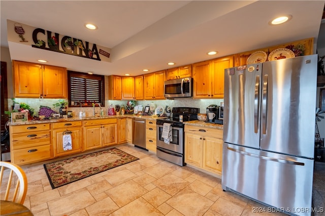 kitchen featuring decorative backsplash, sink, appliances with stainless steel finishes, and light stone counters