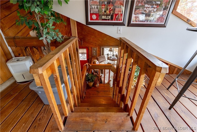 stairway with wood walls and hardwood / wood-style flooring